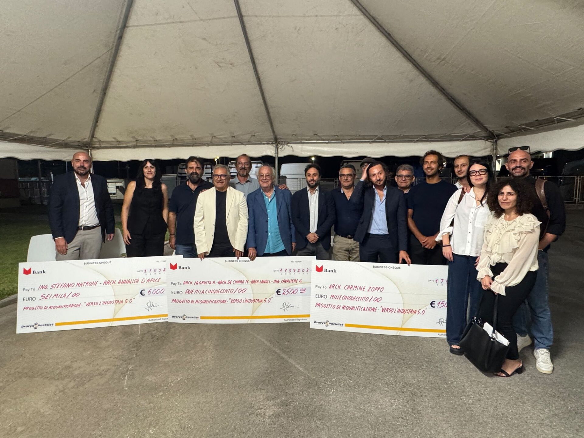 Foto di gruppo dei premiati con i tre assegni sotto il tendone